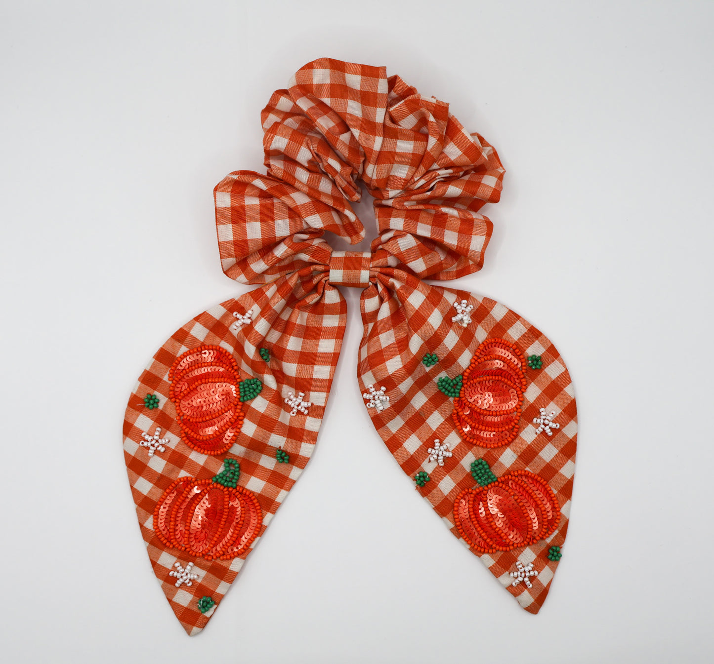 Orange and white checkered scrunchie with pumpkin design on a white background