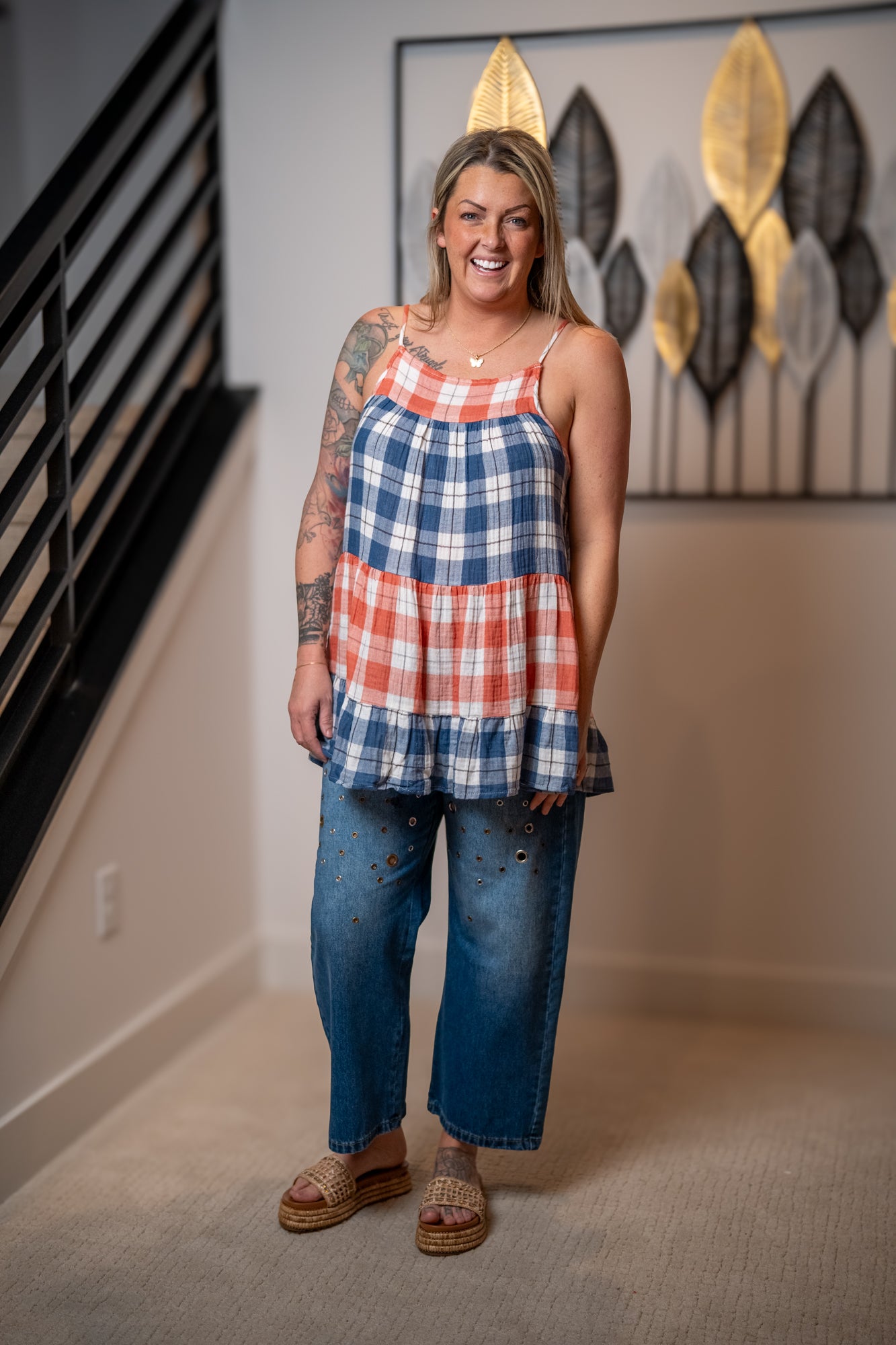 Woman wearing a plaid red blue and white tank top and jeans