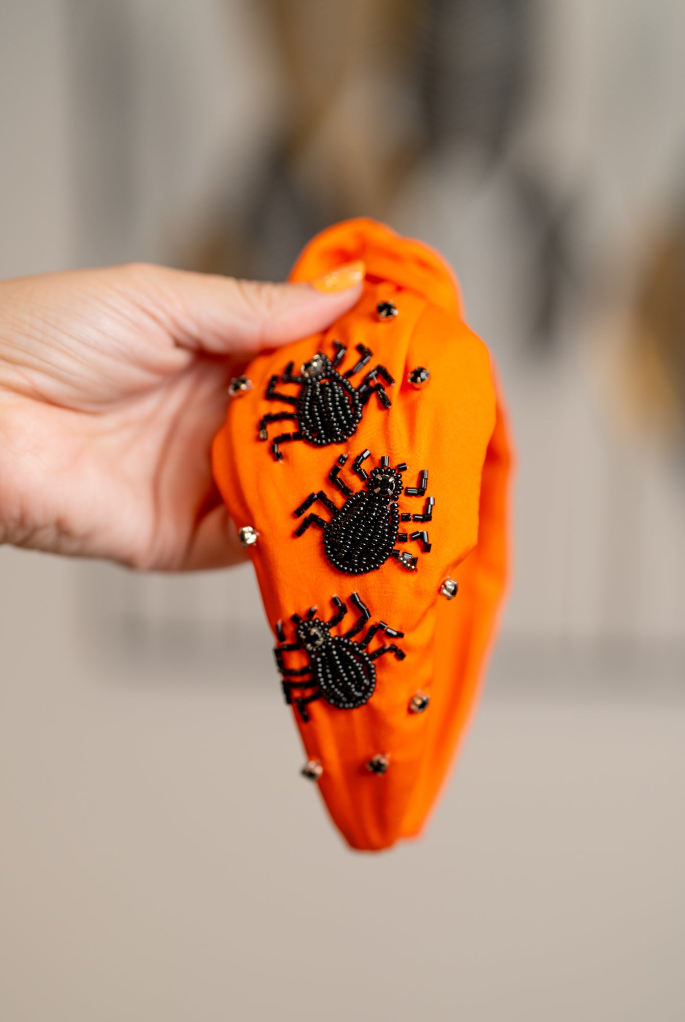 Hand holding an orange Halloween-themed candy container with black spiders on a blurred background