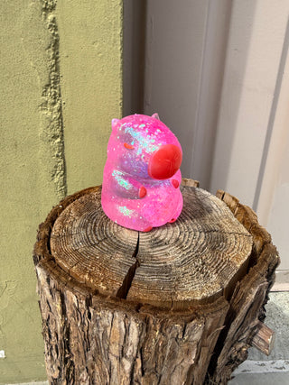 Pink and red object on a wooden log with a neutral background