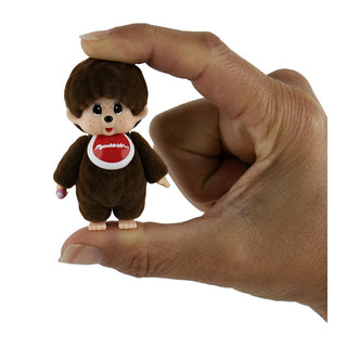 World's Smallest Monchhichi brown plush toy held between fingers showing miniature size