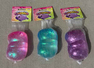Three colorful glittery toys with packaging on a gray surface
