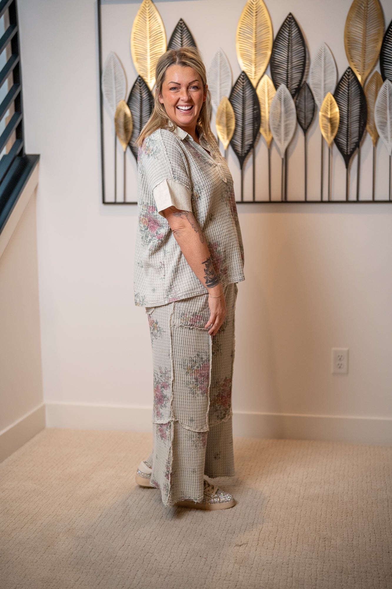 Woman in a floral outfit standing in a room with decorative wall art.