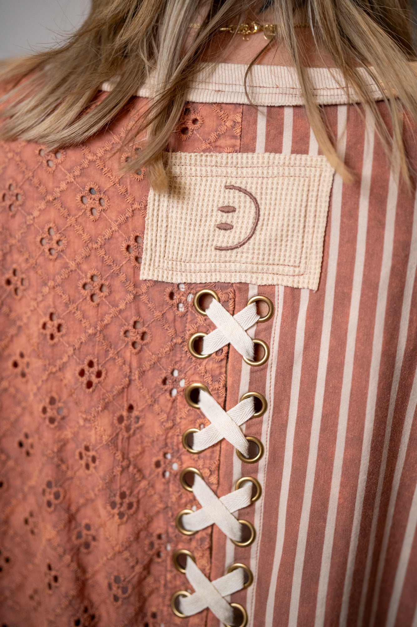 Back detail of Oli and Hali lace up top with crochet fabric, striped panels and tie closure