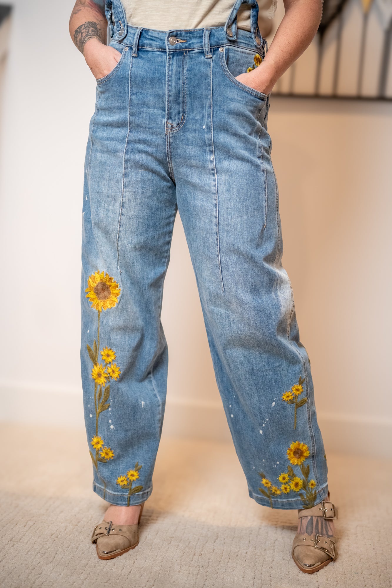 Close up of sunflower embroidered denim overalls with wide leg fit and vintage wash