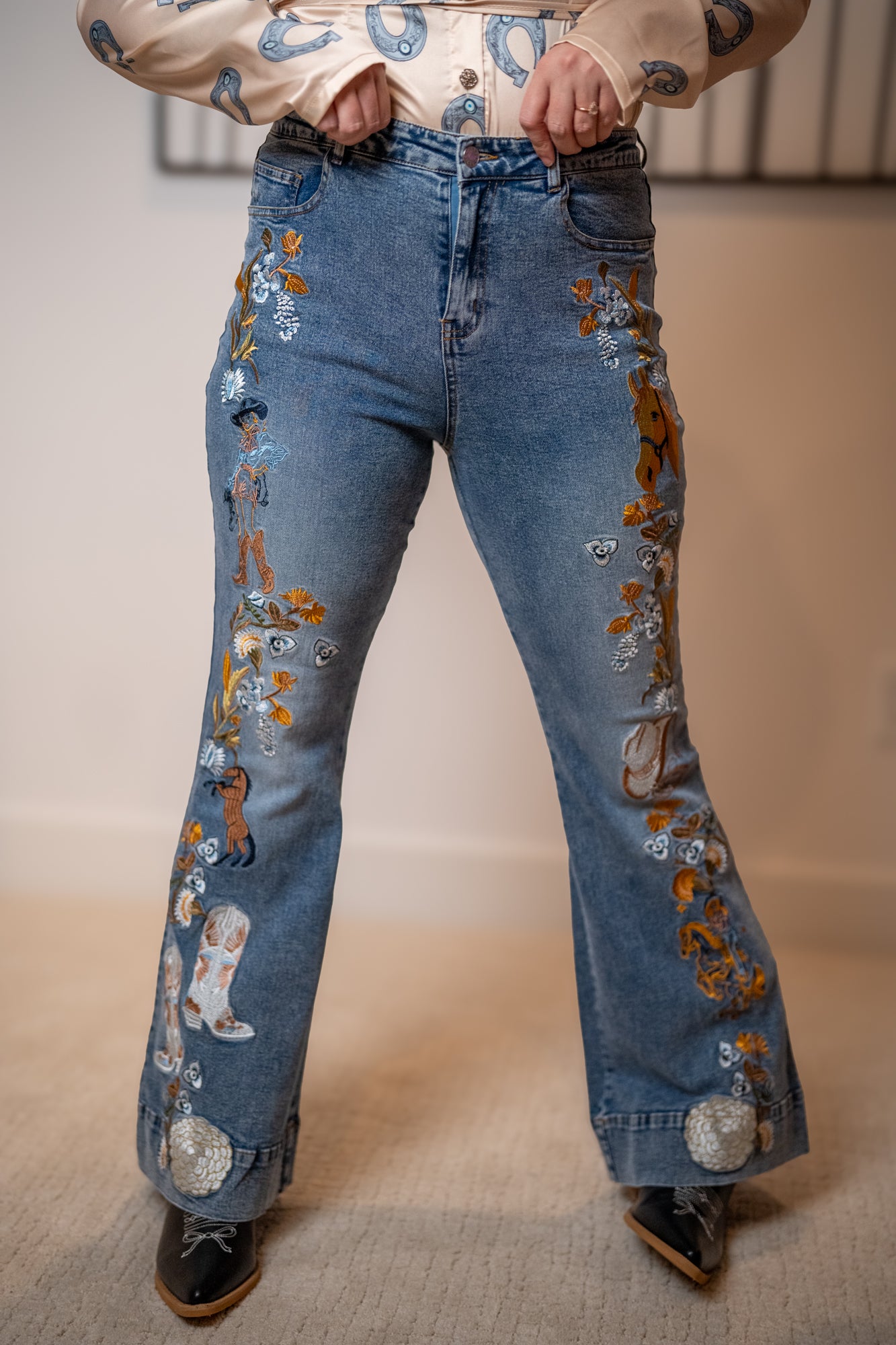 Blue jeans with decorative elements worn by a person on a neutral background