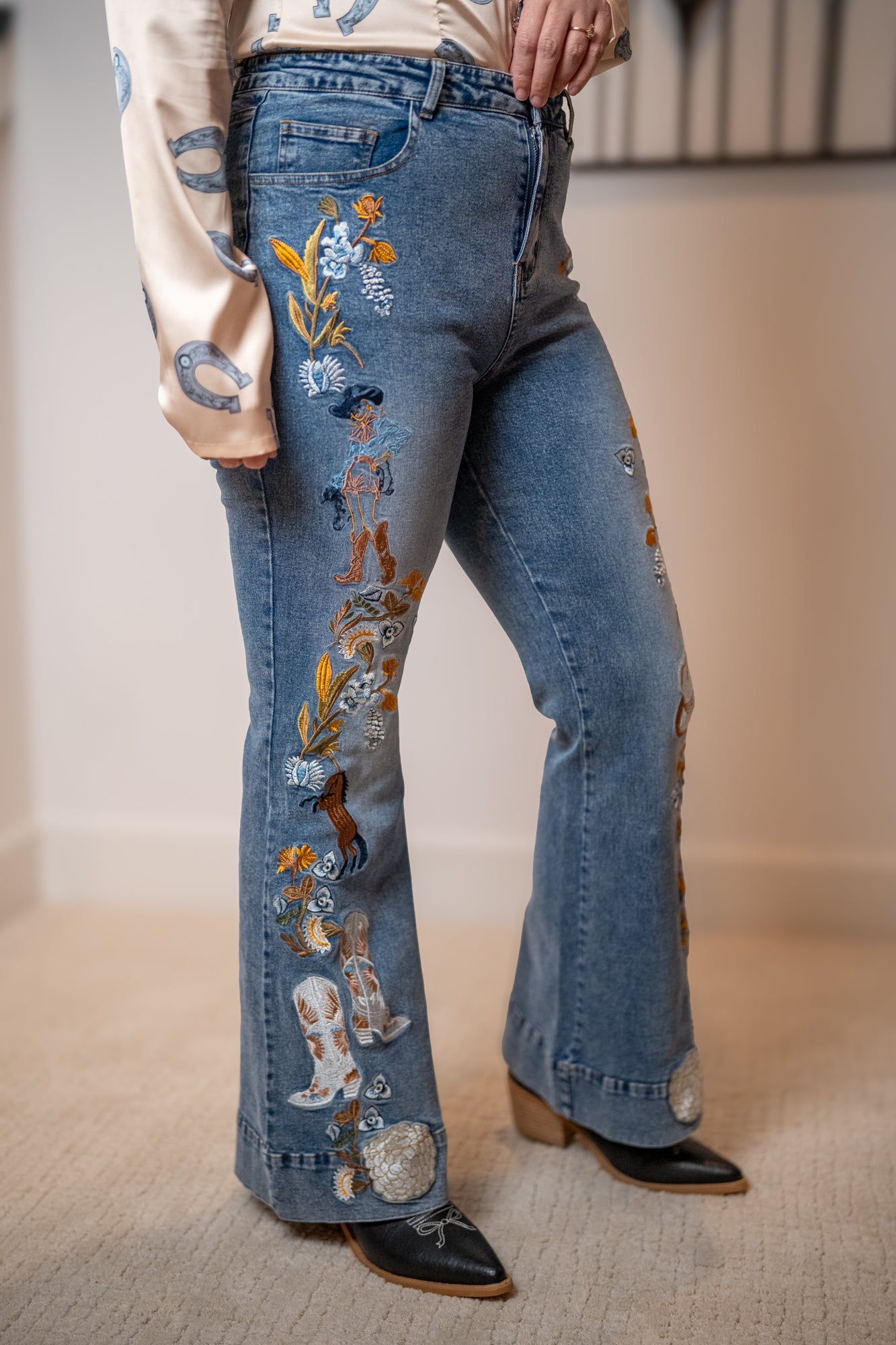 Flared jeans with western embroidered designs worn by a person with boots on