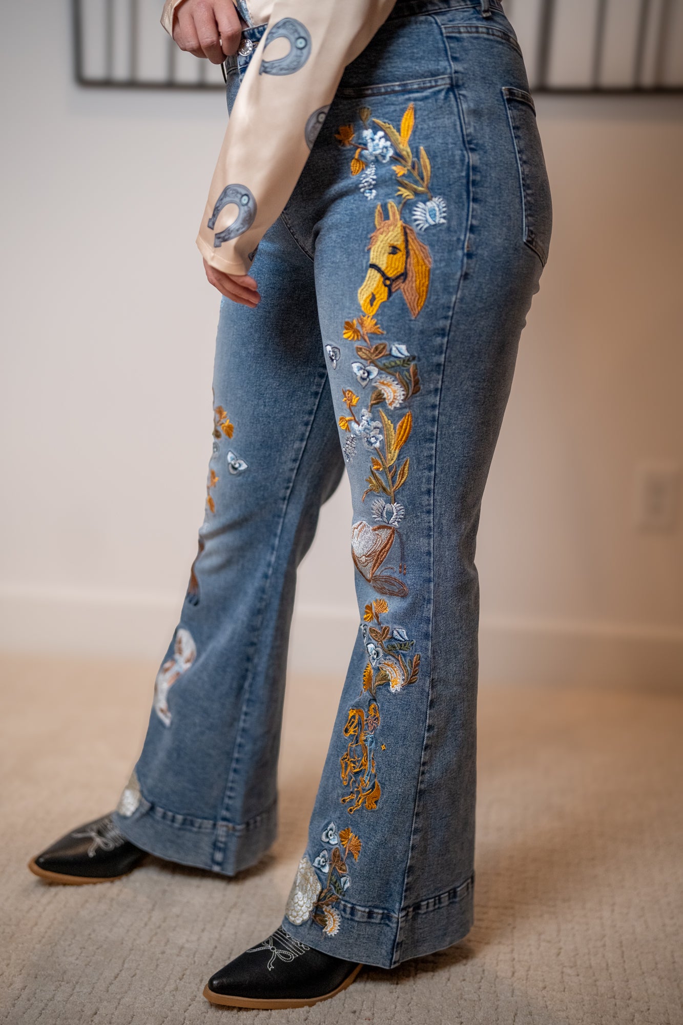 Flared jeans with floral and horese head embroidery worn.