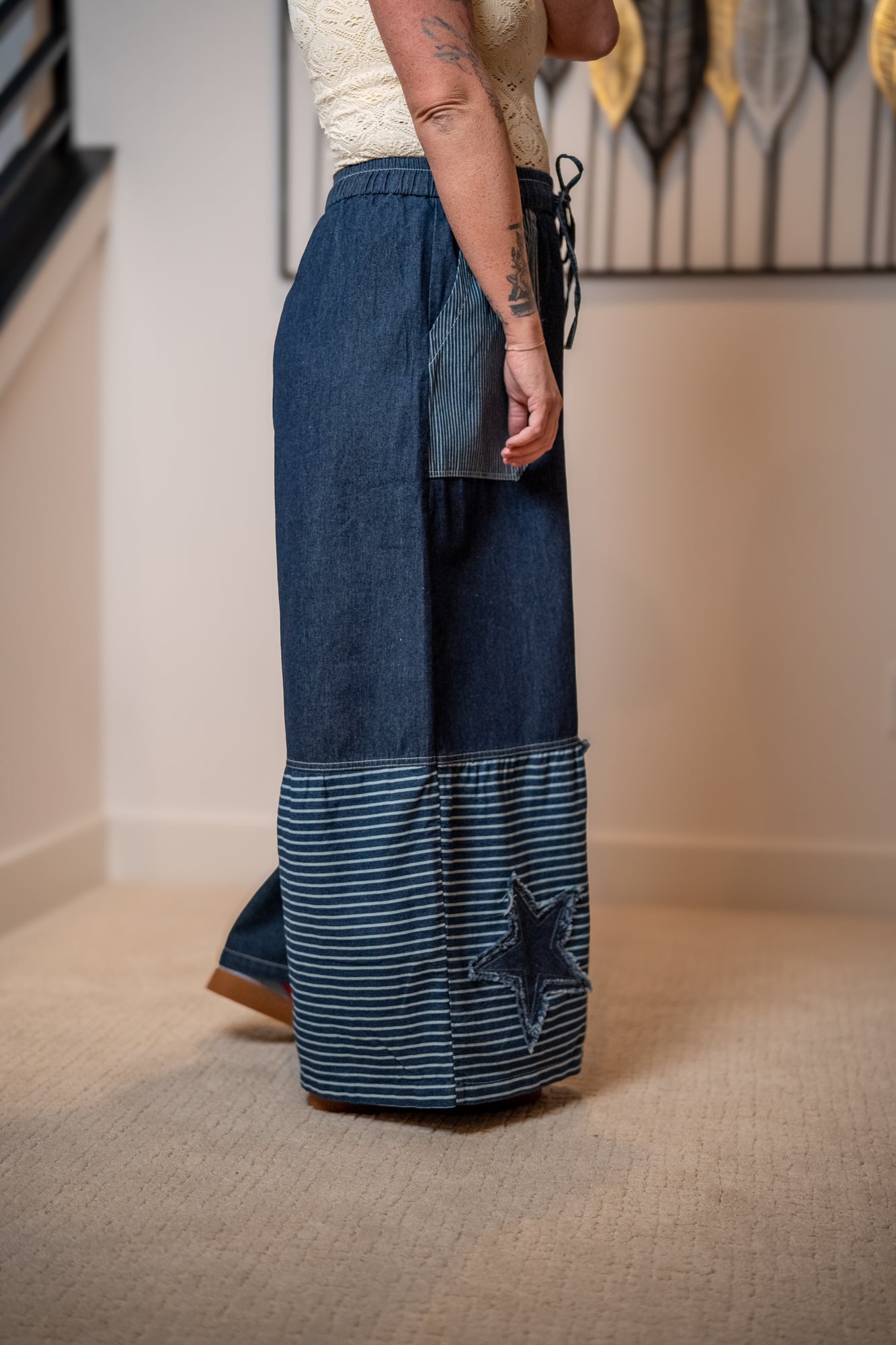 Person wearing blue patchwork pants with a star design indoors.