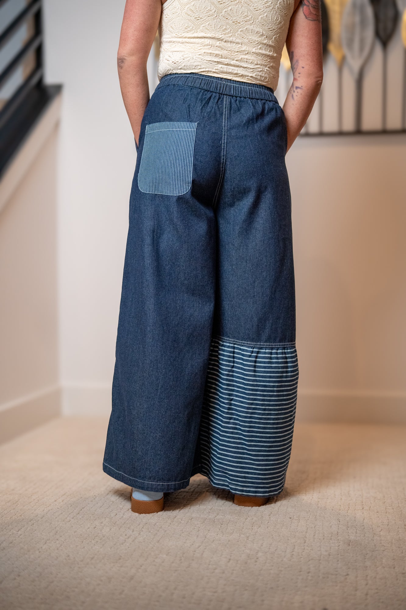 Person wearing blue patchwork pants with a neutral background