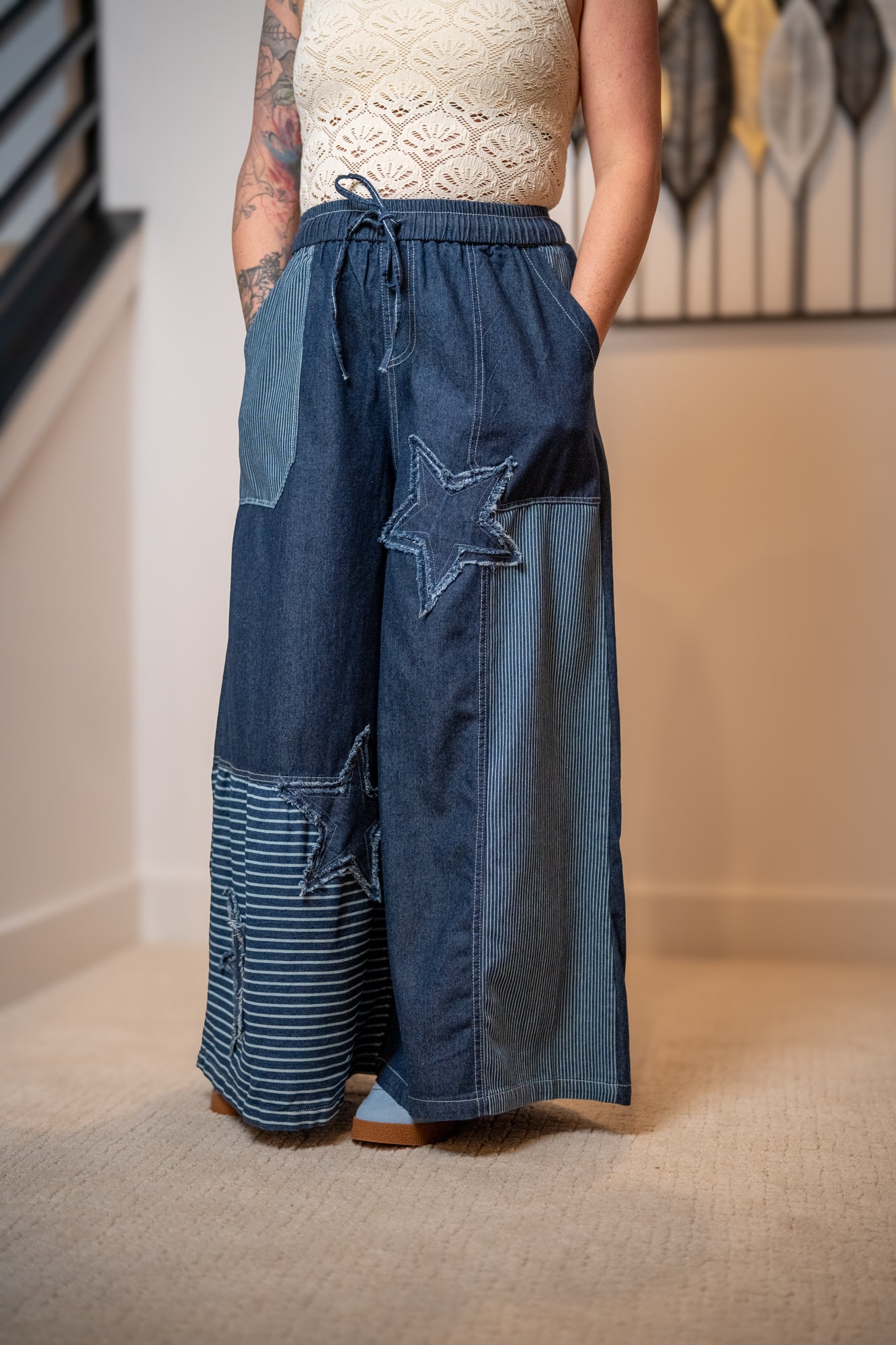 Person wearing blue denim pants with star design in a room.
