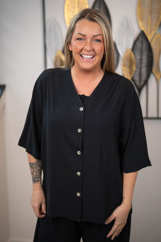 Woman wearing a black blouse with buttons in an indoor setting