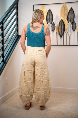 Person wearing a blue top and beige pants in a room with decorative wall art.