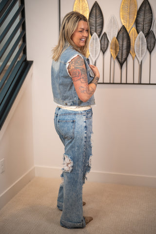 Woman wearing a denim outfit standing in a room with decorative wall art.