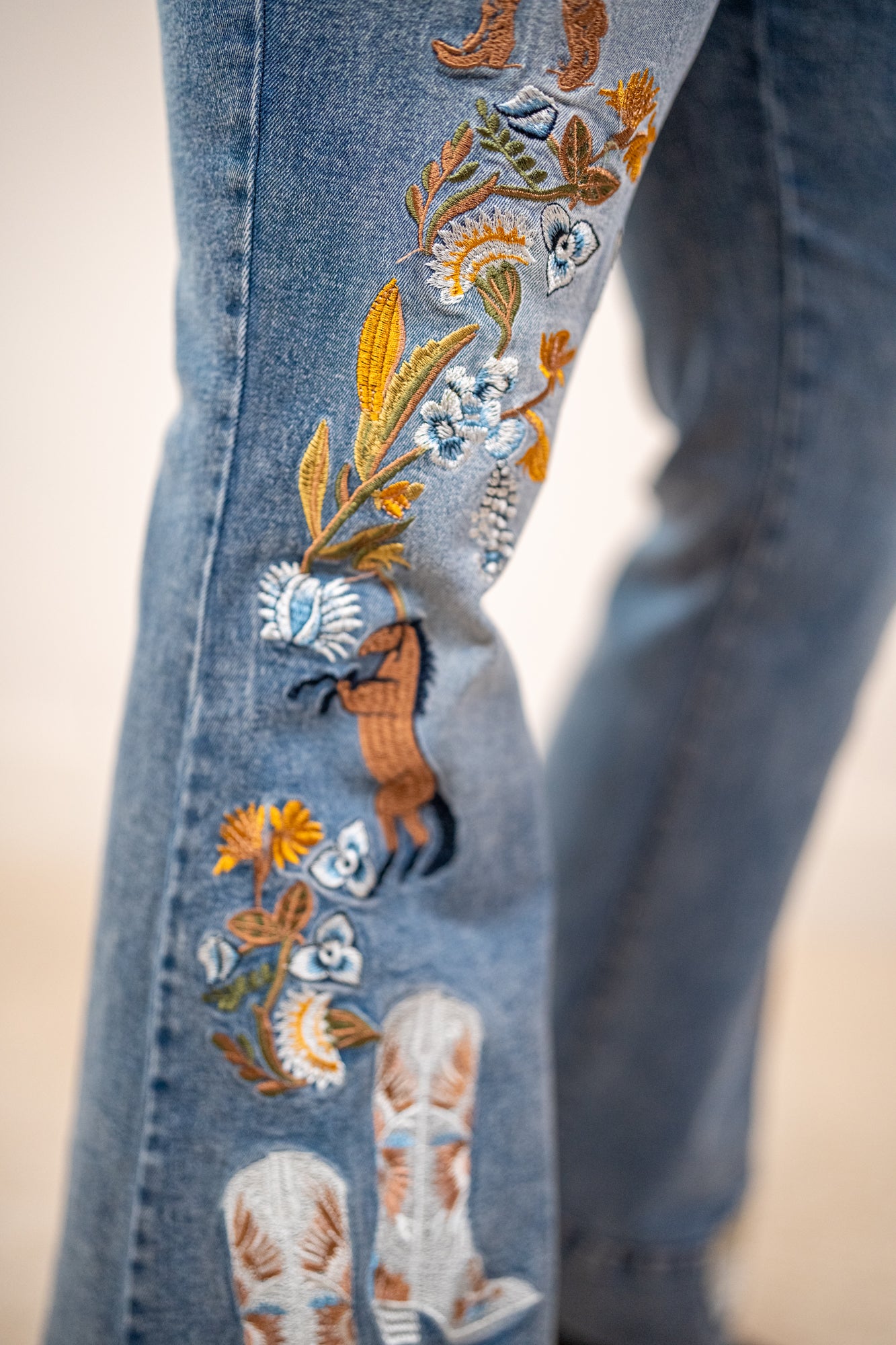 Close-up of blue jeans with intricate floral and horse embroidery 