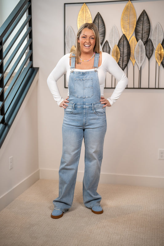 Risen light wash wide leg denim overalls front view styled with white long sleeve top