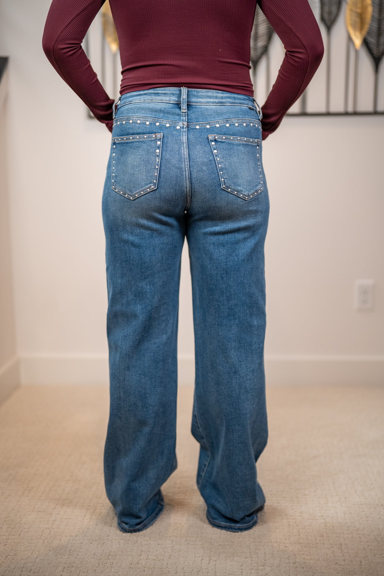 Back of risen medium wash high rise jeans with wide leg fit and silver stud detailing on pockets and seams
