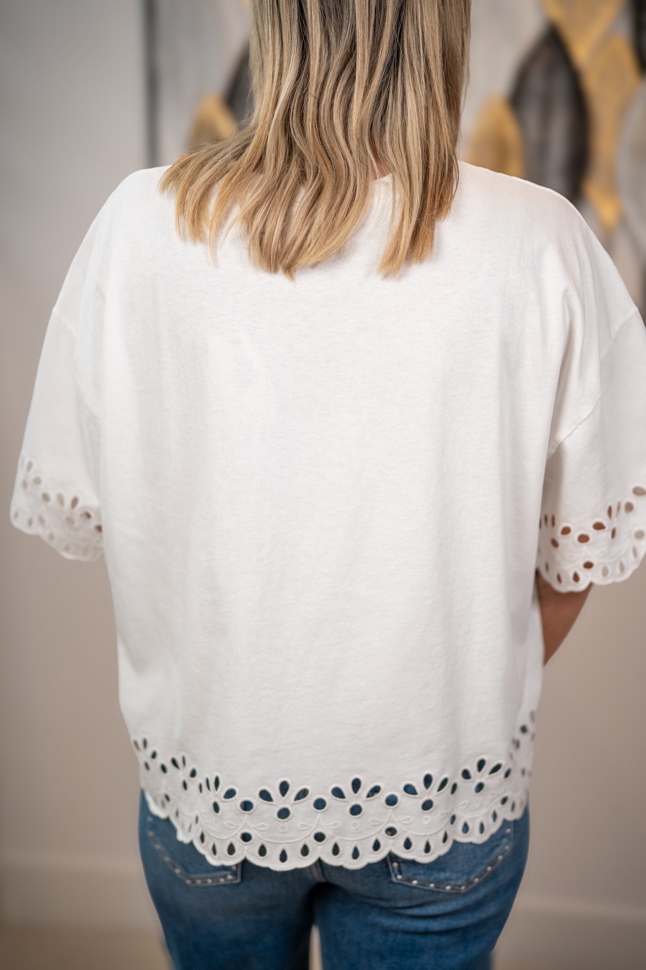 Back view of Easel white eyelet hem top with scalloped embroidery detail and relaxed fit
