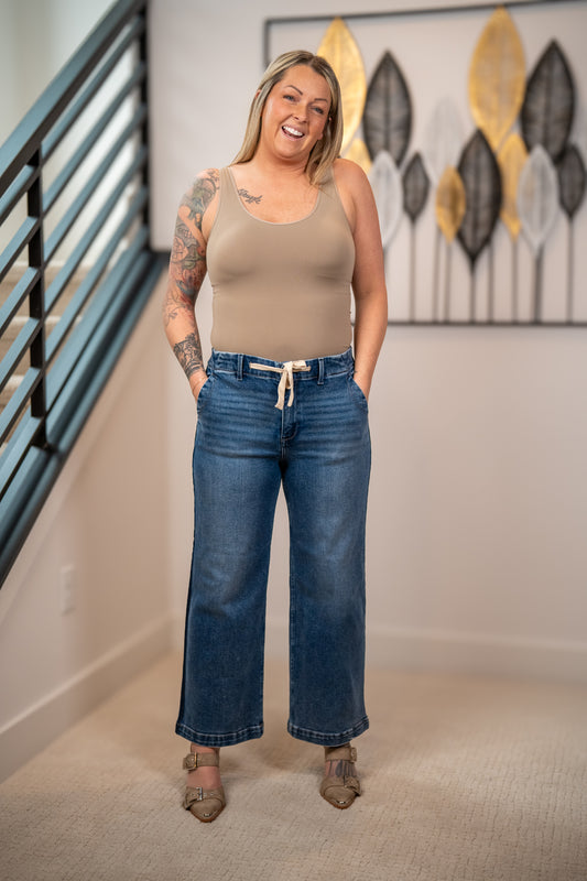 Risen elastic band high rise cropped wide leg jeans with drawstring waist front view styled with tan tank top