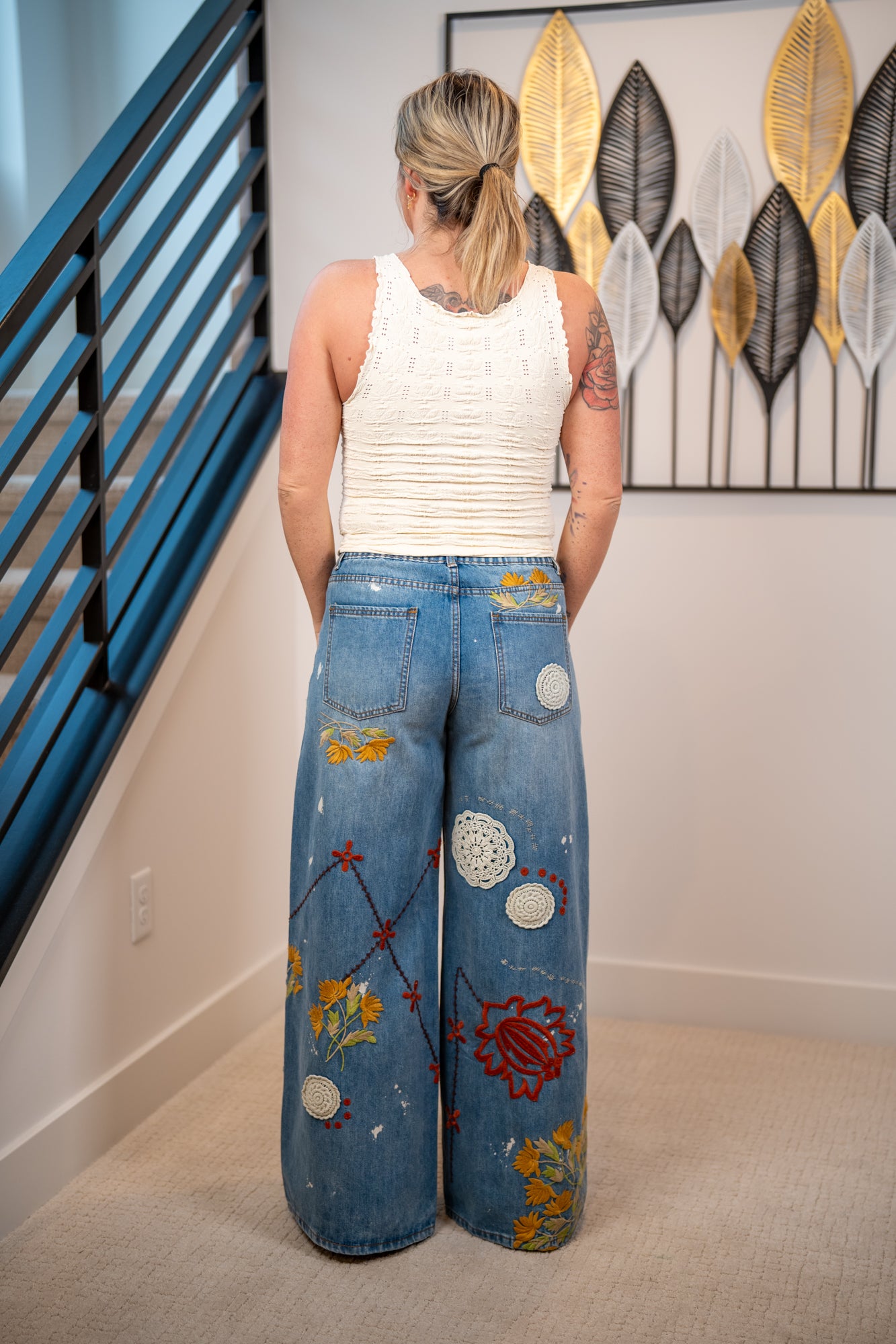 back view Boho-inspired embroidered wide leg jeans with floral patterns and crochet accents in medium wash denim