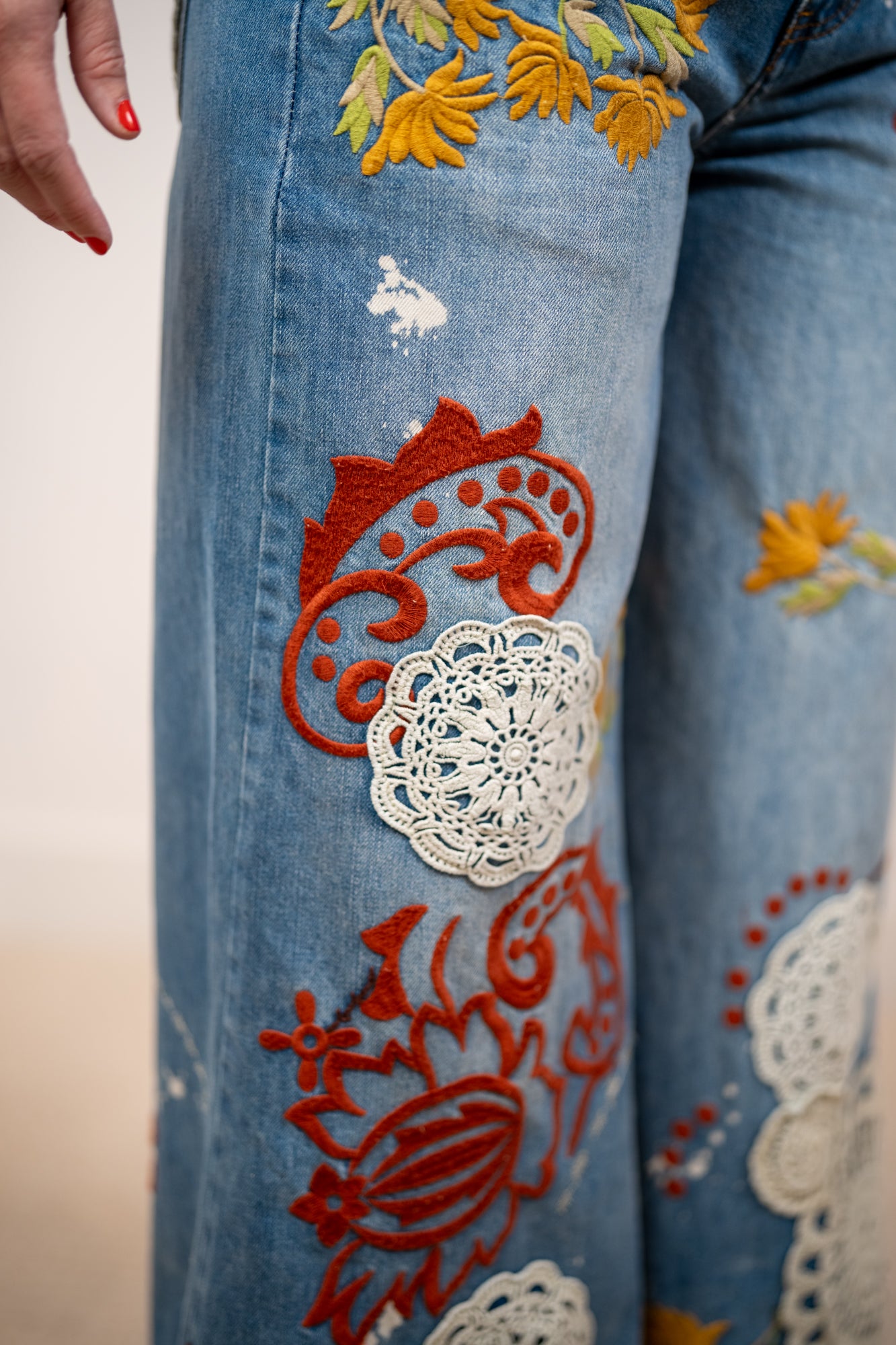 Medium wash wide leg denim jeans with red floral embroidery and cream lace appliqué by Oli and Hali
