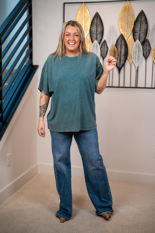 Woman wearing a dark teal oversized shirt untucked and jeans 