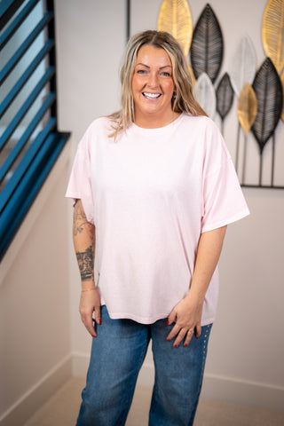 Woman wearing a light pink oversized t-shirt and jeans 