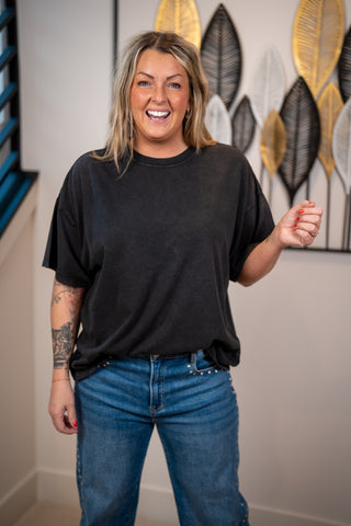 Person wearing a black t-shirt boxy tucked in to denim jeans