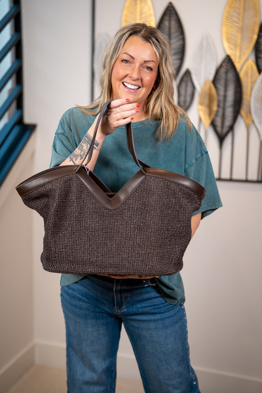 Women holding the chocolate brown tote bag showing the V-notch detail