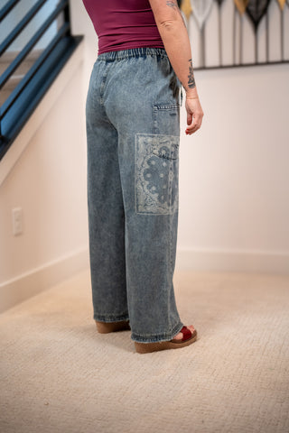 Person wearing blue jeans with a floral patch in an indoor setting