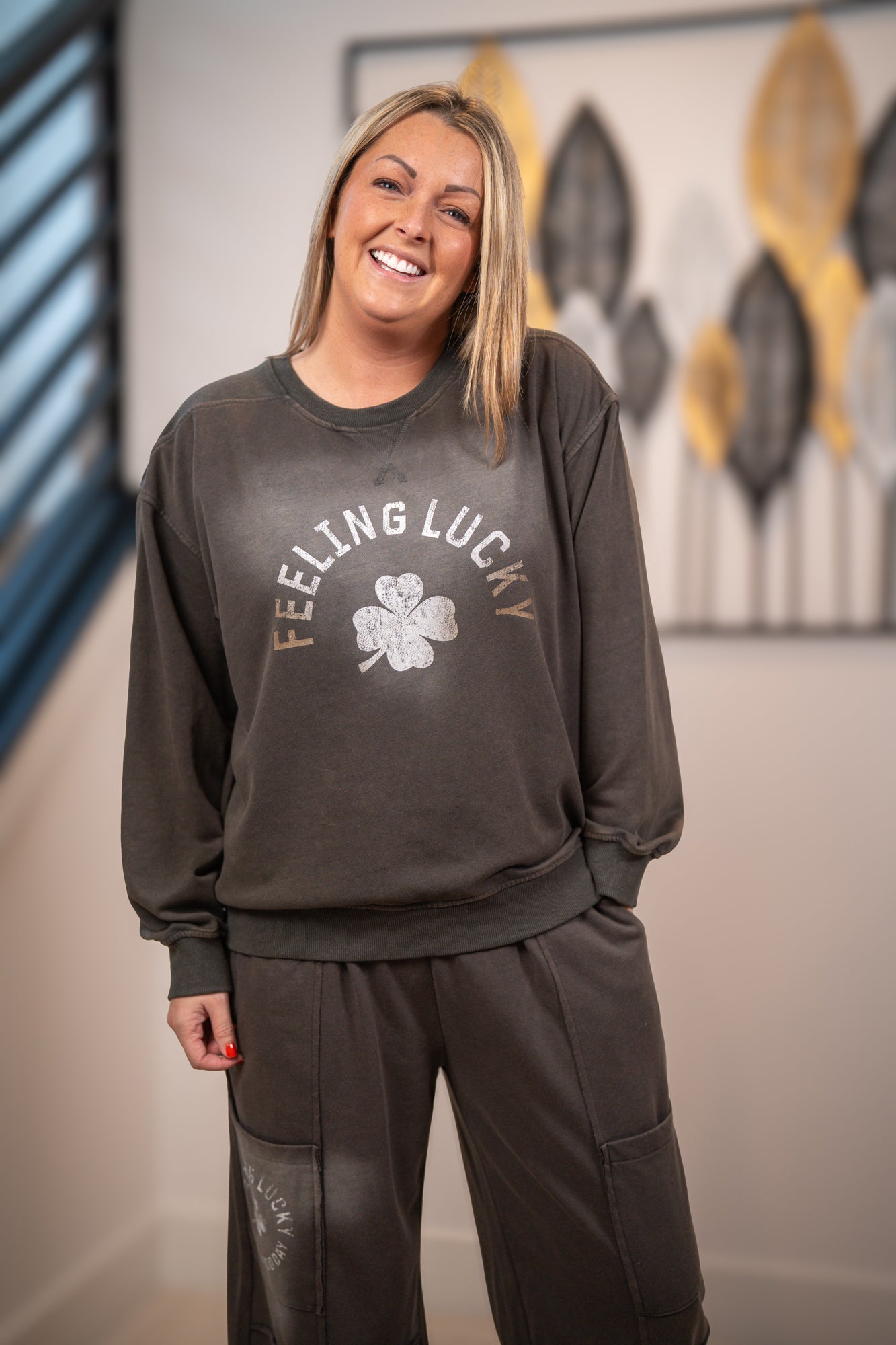 Person wearing a dark gray sweatshirt with 'Feeling Lucky' text and a clover graphic, standing indoors.