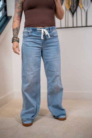 Person wearing blue jeans and a brown top in an indoor setting