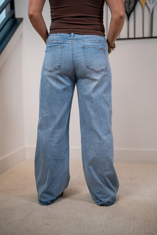 Person wearing blue jeans with a plain background