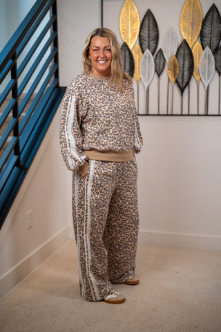 Woman in a leopard print outfit standing in a room with decorative wall art.