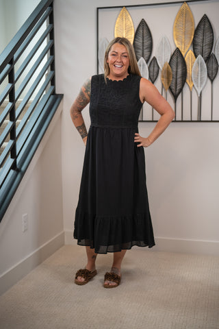 Woman wearing a black dress standing in a room with decorative wall art.