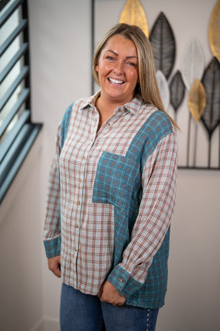 Woman wearing a plaid shirt with blue accents in a room with decorative wall art.