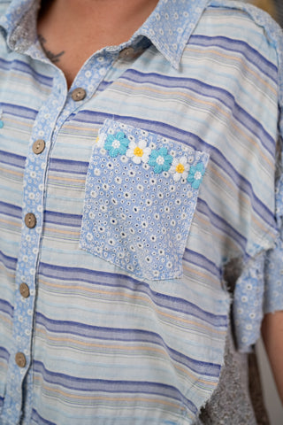 Close-up of a striped shirt with a floral pocket detail