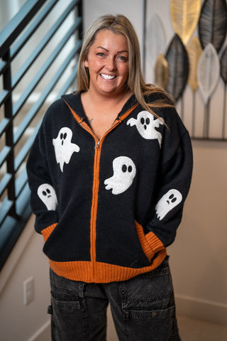 Black zip-up hoodie with white ghost patches and orange ribbed trim