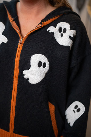 Black zip-up hoodie with white ghost patches and orange trim accents