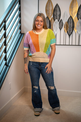 Woman wearing a colorful striped sweater and jeans queen of sparkles.
