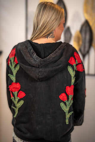 Black acid-wash zip-up hoodie with red floral embroidery on sleeves, back view
