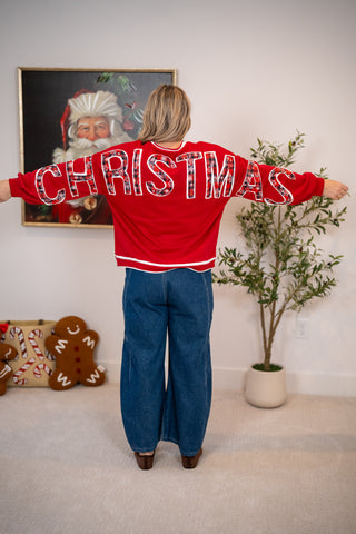 Red Christmas spirit jersey sweatshirt with bold festive lettering across back and sleeves