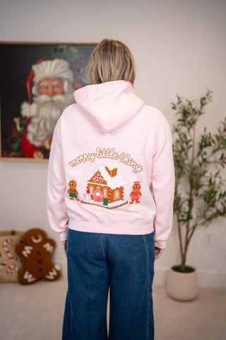 Light pink hoodie with gingerbread house and merry little thing graphic on back