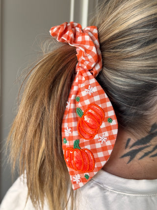 Orange white gingham scrunchie with sequin beaded pumpkin embellishments worn in ponytail