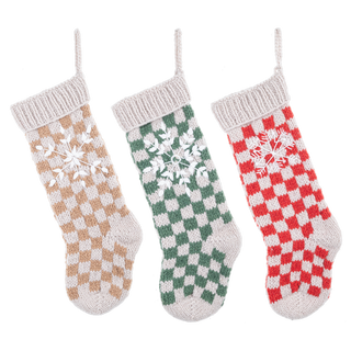 Three knit buffalo check Christmas stockings in tan, green, and red with embroidered snowflakes