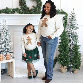 Woman and girl wearing matching cream gingerbread sequin patch sweatshirts in holiday setting