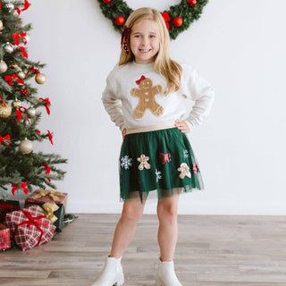 Girl wearing cream gingerbread sequin patch sweatshirt with green tulle skirt